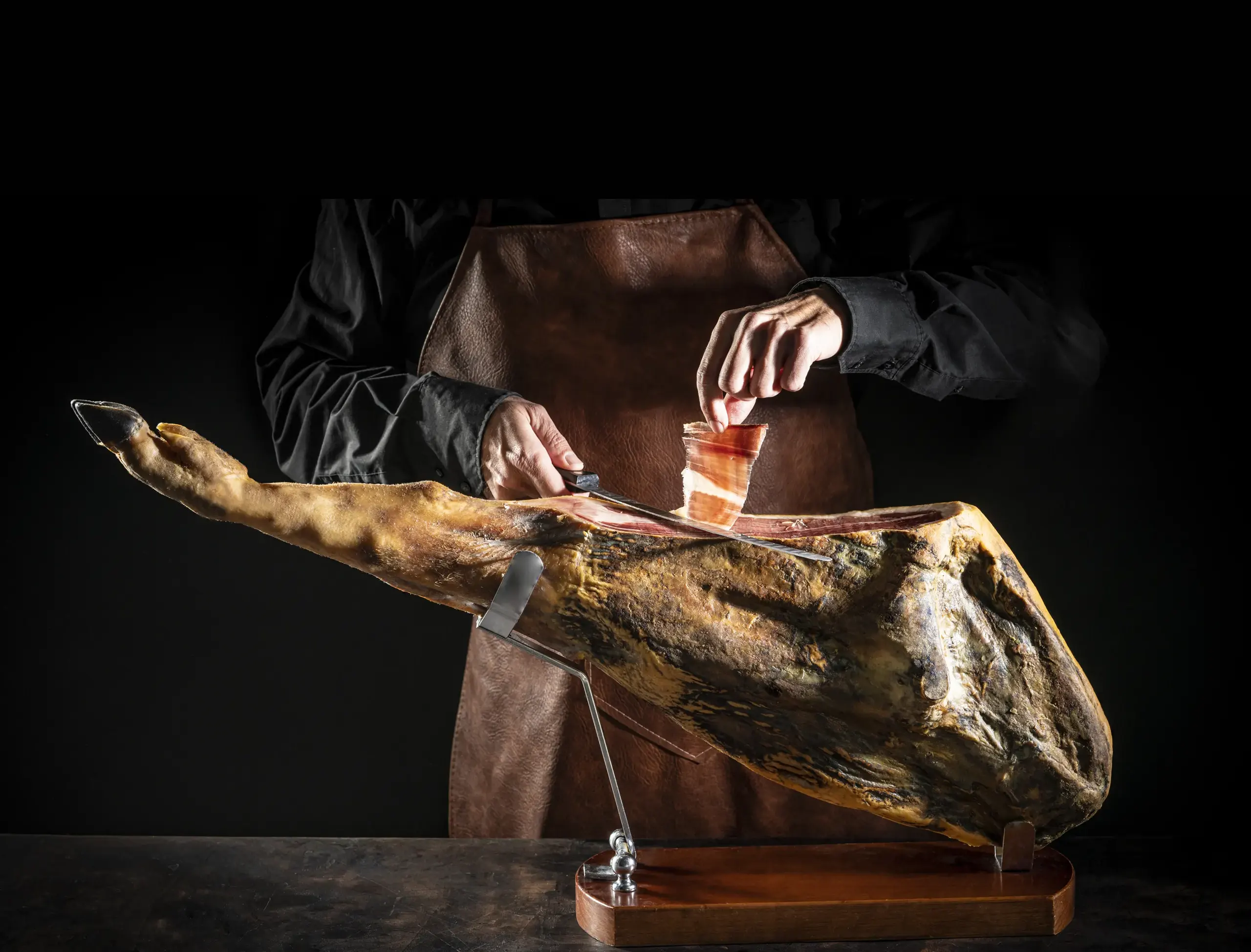 Corte a cuchillo de una pieza ibérica en su jamonero